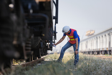 Fototapeta premium Railway Technician Inspecting Train Undercarriage at Rail Yard