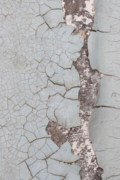 Peeling paint on the wall. Old concrete wall with cracked flaking paint. Weathered rough painted surface with patterns of cracks and peeling. High resolution texture for background and design. Closeup