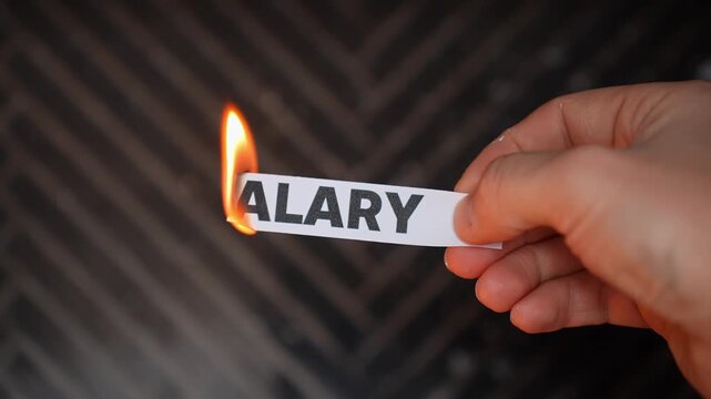 Hand burns a paper label reading &ldquo;SALARY,&rdquo; symbolizing leaving paycheck dependence&mdash;financial independence, new income streams, and freedom from a fixed wage. Dark copy space.