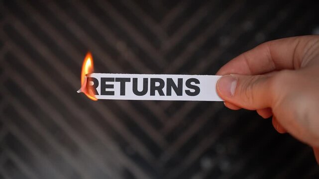Hand burns a paper label reading &ldquo;RETURNS,&rdquo; symbolizing no-return policy&mdash;final sale, keep the purchase, and commitment to the deal. Dark background with copy space.