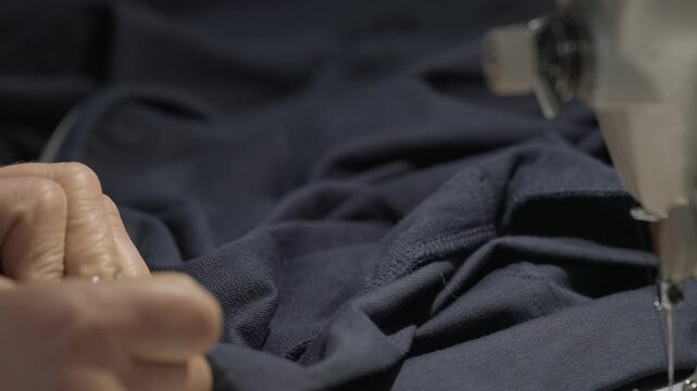 Close up of hands cutting loose thread and positioning fabric before sewing on machine