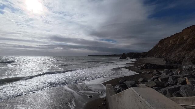 waves and surf coming ashore on Benvoy Beach Waterford Ireland dramatic early spring clouds and full tide epic locations Ireland