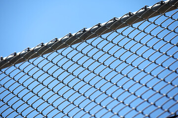 Close-Up View of Metal Chain Link Fence Against Bright Blue Sky © sakhorn38