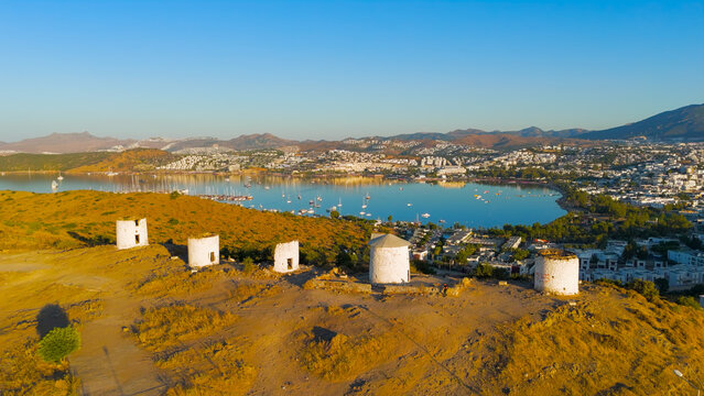 Bodrum, Turkey. Morning aerial drone view of historic Bodrum windmills on hill with Gokova Bay in background under bright summer sun.. Aerial View