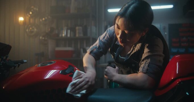 Technician in Overalls Polishing Sport bike With Microfiber Cloth Until Glitters. Young Woman Admiring Reflections, Sunbeams on Vehicles Glossy Body After Successful Repair Session. Garage Atmosphere.
