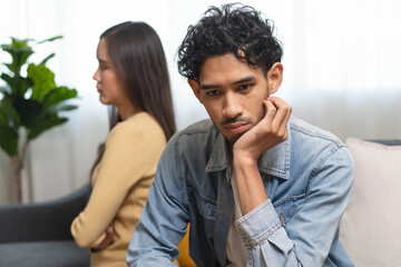 Obraz premium Family problem concept. Tension in relationship between married couple, husband and wife staying sitting separate after quarrel in the living room.