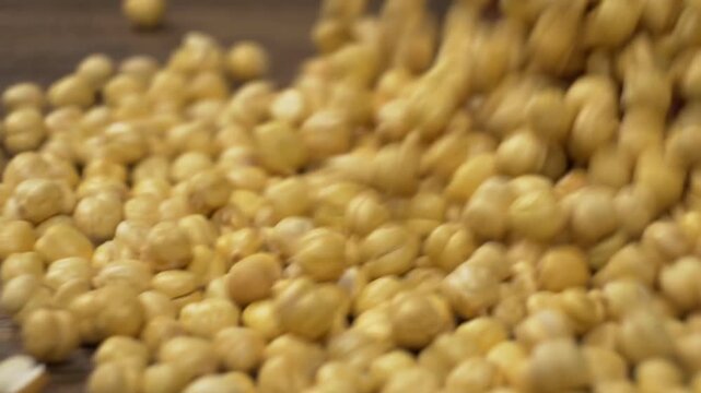 Spilling chickpeas on a wooden surface for vegan meal preparation dynamic close-up shot