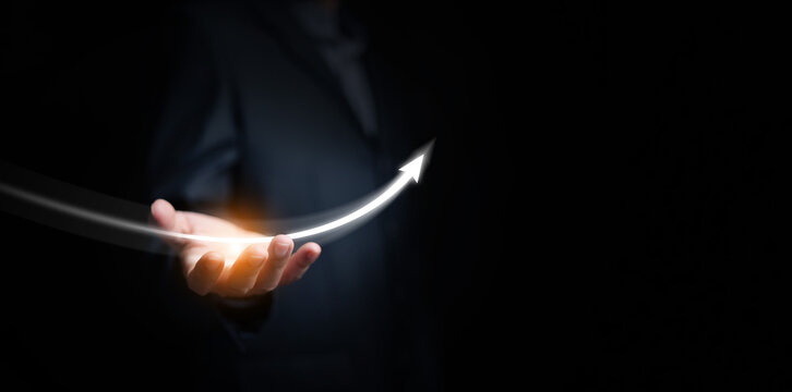 Recovery concept. Hand supporting a white glowing arrow curving from a downward trend into smooth upward upturn. Recovering business, economy, finance, investment, career, market, personal growth.