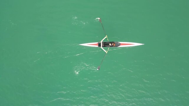 Single Scull Rower Overhead On Turquoise Water, Focused Athlete Executing Steady Strokes, Narrow Boat Wake