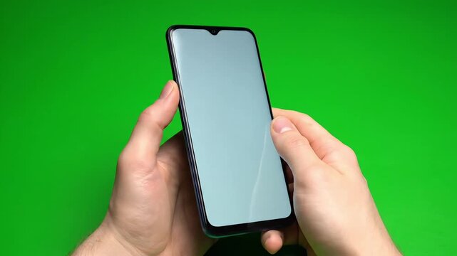 Hands holding smartphone with blank white screen on green background