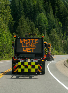 Canada, BC, Valemount.  Road crew painting line on the side of highway 5 in mountainous terrain.