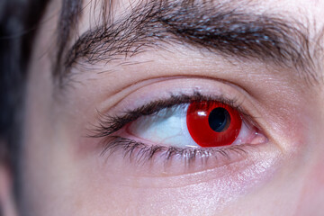 Obraz premium A dramatic portrait of a male eye with intense red contact lenses capturing a captivating and mysterious gaze