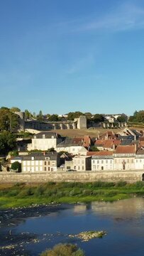 Charming view of La Charite sur Loire with traditional houses and ancient stone walls along the Loire River under a clear blue sky.