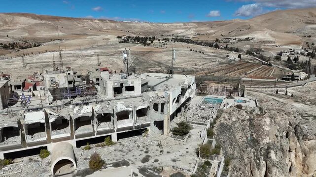 A wide aerial drone panorama of Ma'loula, Syria, highlighting the ancient village and the dramatic rocky cliffs of the Qalamoun range