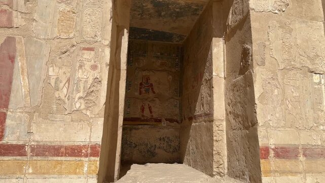 A static shot showing a well-preserved colorful wall painting of an Egyptian pharaoh inside a stone niche at the Temple of Hatshepsut in Luxor