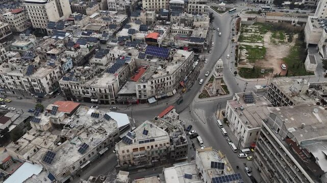 Aerial drone view of the historic Bab al-Faraj Clock Tower and busy city center in Aleppo, Syria, featuring traditional architecture and modern building roads infrastructure