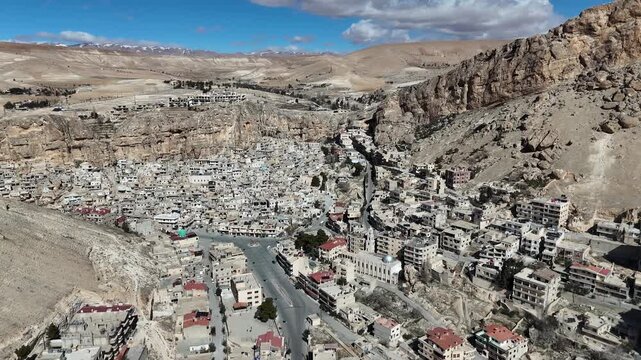 Cinematic perspective of the ancient village of Ma'loula, Syria, showing architecture into the steep Qalamoun Mountains