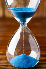 Blue retro hourglass to measure time on wooden table