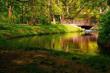 Naklejka premium Beautiful calm running river and wooden bridge the spring park