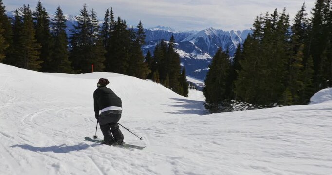 Follow-camera shot of a playful skier cruising down the slope in LAAX, hitting natural side hits and throwing snow sprays. Dynamic freestyle skiing with cinematic alpine winter energy.