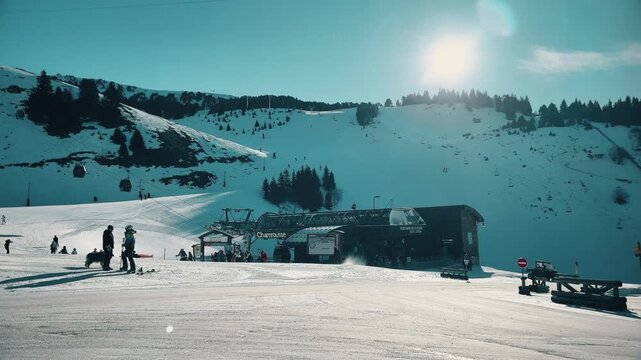 Sunny ski resort slopes, silhouettes of people and gondola station in Chamrousse, French Alps