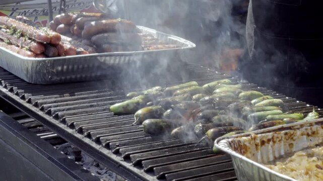 Street food vendor grilling green peppers over open flame at a barbecue stand during a public festival in Cholula Puebla Mexico.