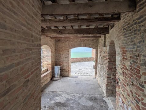 Corridoio storico in mattoni con archi e vista sulle campagne in un borgo antico
