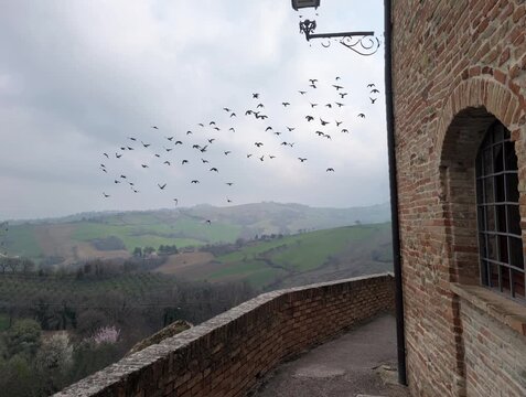 Camminamento sulle mura medievali con vista sulle colline con edifici storici in pietra