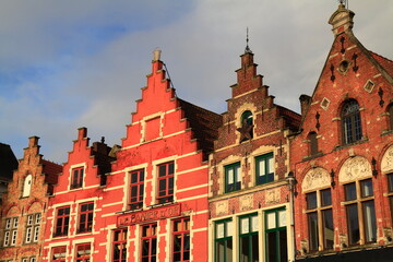 Fototapeta premium Historic red brick buildings with stepped gables overlook vibrant outdoor cafes, Bruges