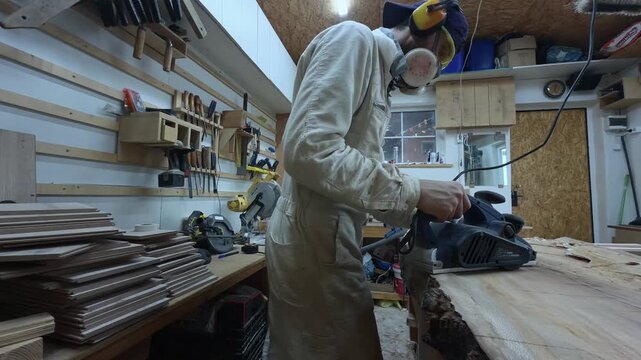 Woodworker in PPE Surfacing Timber Slab highlighting active Dust Extraction Hose Tracking Shot