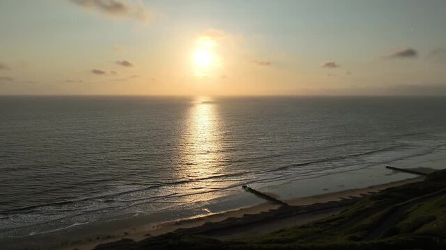 Stunning aerial view of sunrise over North Sea from Mundesley coast with golden sun reflection Norfolk