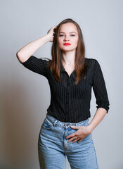 Naklejka premium Junge Frau in Jeans und schwarzer Bluse posiert selbstbewusst vor hellem Hintergrund. Modernes Fashion- und Lifestyleporträt mit Copyspace, Konzept für Stil, Mode und Persönlichkeit.