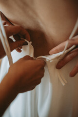 Fototapeta premium Détail des préparatifs de la mariée, main fermant la robe de cérémonie 