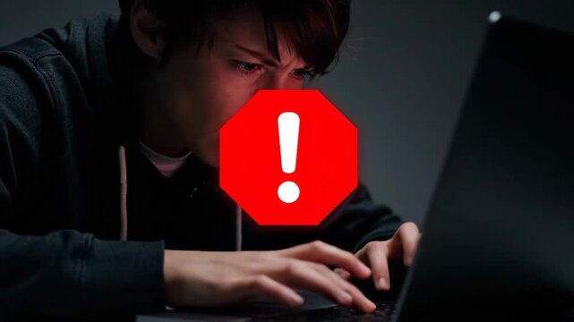 Young male hacker in a dark room gets a critical system error while coding. Cybersecurity threat concept with a red warning alert icon and digital data breach overlay