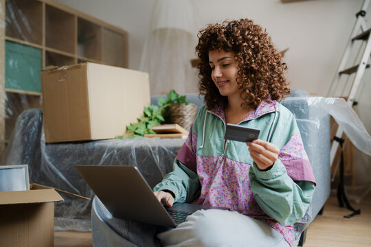 Woman sitting at home making online payment with credit card on laptop