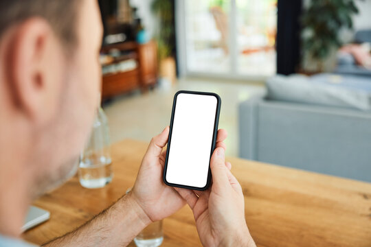Man holding smartphone with blank screen at home living room