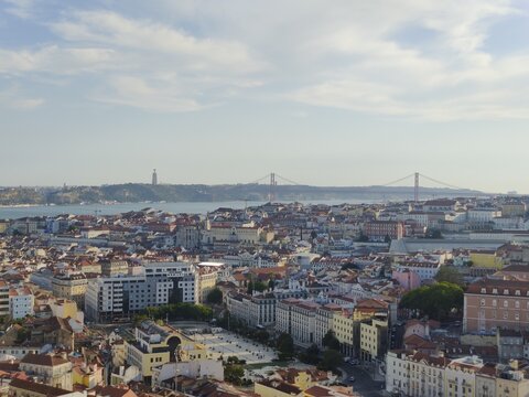 Aerial view of the city's rooftops stretching towards the Tagus River, the Ponte 25 de Abril bridge and the Cristo Rei statue in the distance, Lisbon, Lisbon, Portugal.