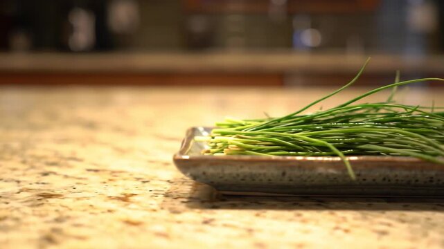 Fresh chives on a ceramic plate on granite countertop, kitchen herb, food ingredient.