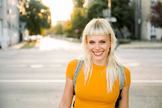 Portrait of smiling woman with blonde hair in orange shirt outdoors