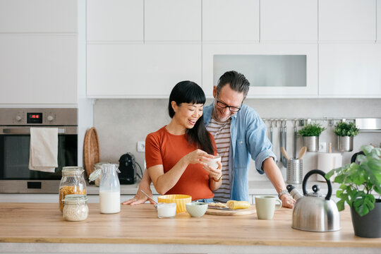 Smiling couple preparing healthy breakfast together in kitchen