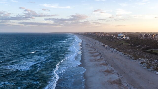 Aerial view of the meeting point of the deep blue sea and the light-colored sandy beach, with buildings lining the coast, Amelia Island, Florida, United States.