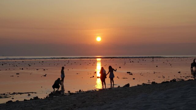 unrecognizable People taking photos during beautiful sunset on the beach gilit