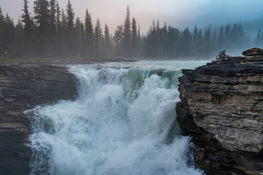 Athabasca Falls at sunrise with mist and rocky cliffs in Alberta