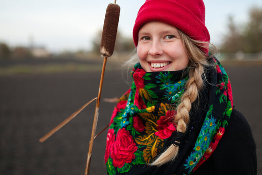 Smiling woman outdoors in autumn with red hat scarf and cattail