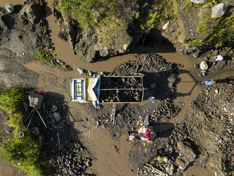 Aerial view of a truck surrounded by workers amidst the muddy Woro River and rocky terrain, Klaten Regency, Central Java, Indonesia.