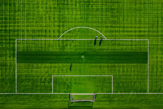 Aerial view of a vibrant green soccer field, the white lines sharply defining the boundaries, contrasting with the lush grass, Warsaw, Masovian Voivodeship, Poland.
