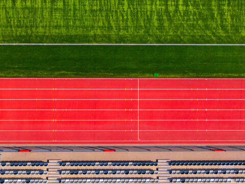 Aerial view of vibrant red running tracks contrast against the lush green field and rows of stadium seating, Warsaw, Masovian Voivodeship, Poland.