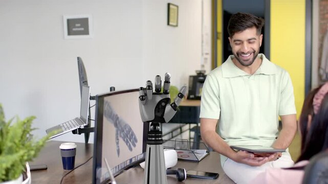 Vertical video: Woman controlling prosthetic hand at desk, screen mirroring gestures for tech demo
