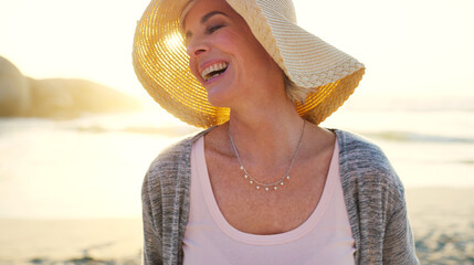 Thinking, sunset or woman with laugh at beach for summer holiday, weekend break or funny memory. Daydreaming, evening and happy mature person with hat at seaside for getaway trip, fresh air and joke