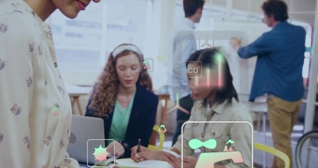 Working team wearing biz-casual using laptop noting at board in office with bike-wheel and AR-UI